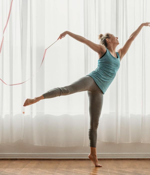 A young woman practicing gentle rhythmic movements in a sunlit studio.